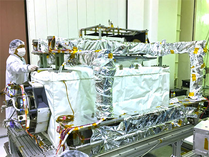 Worker in lab coat, hair cover and mask working with foil covered box - ECOSTRESS