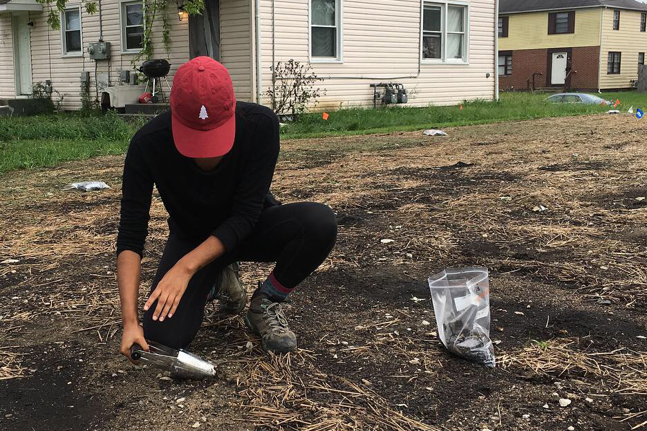 man taking soil sample by house